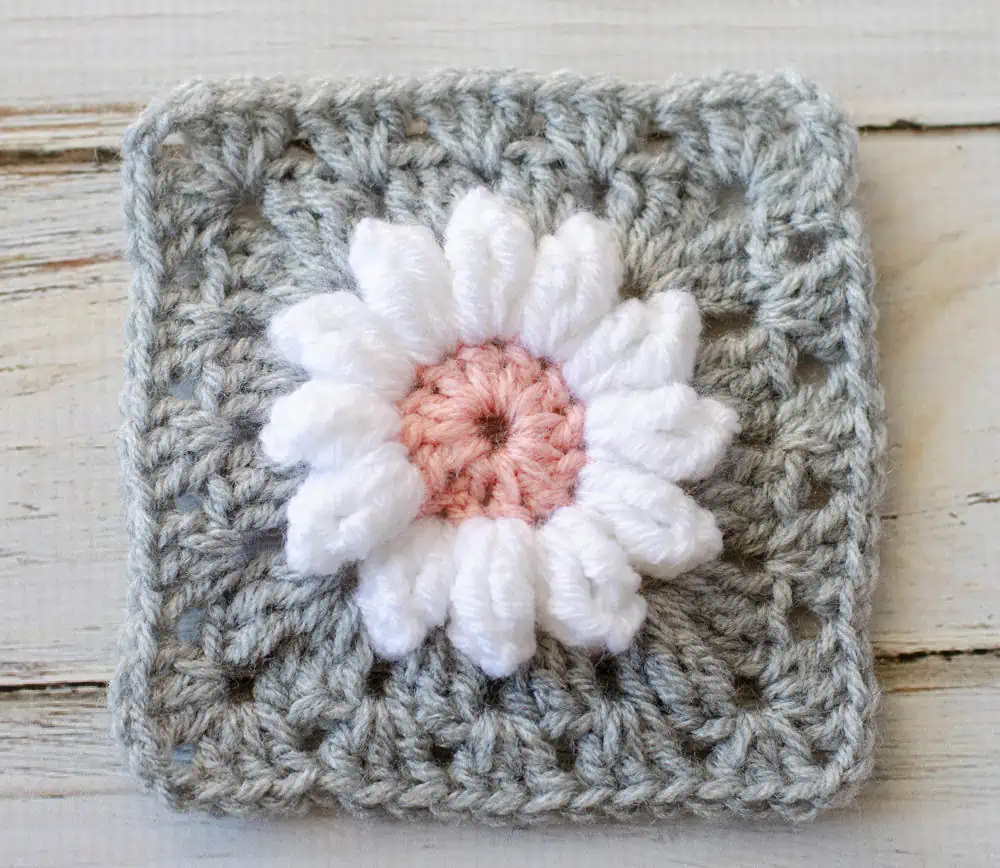 Completed daisy granny square in pink, white and gray