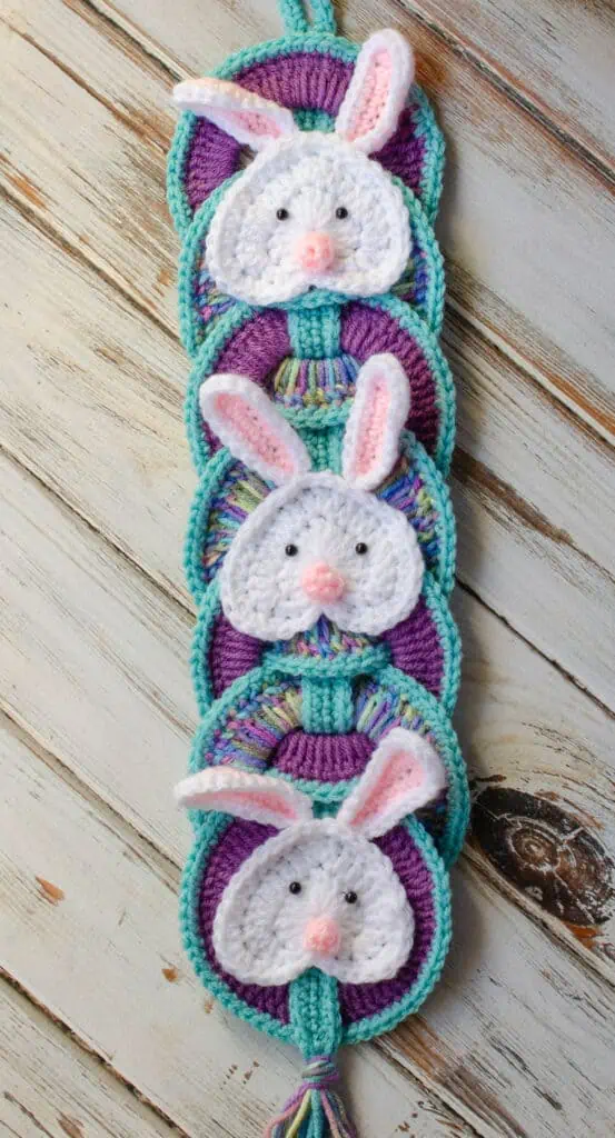 Crochet bunny wall hanging with 3 white bunnies with pink ears and noses on crochet rings.