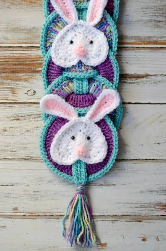 Up close image of crochet white bunny appliqué on blue and purple rings.