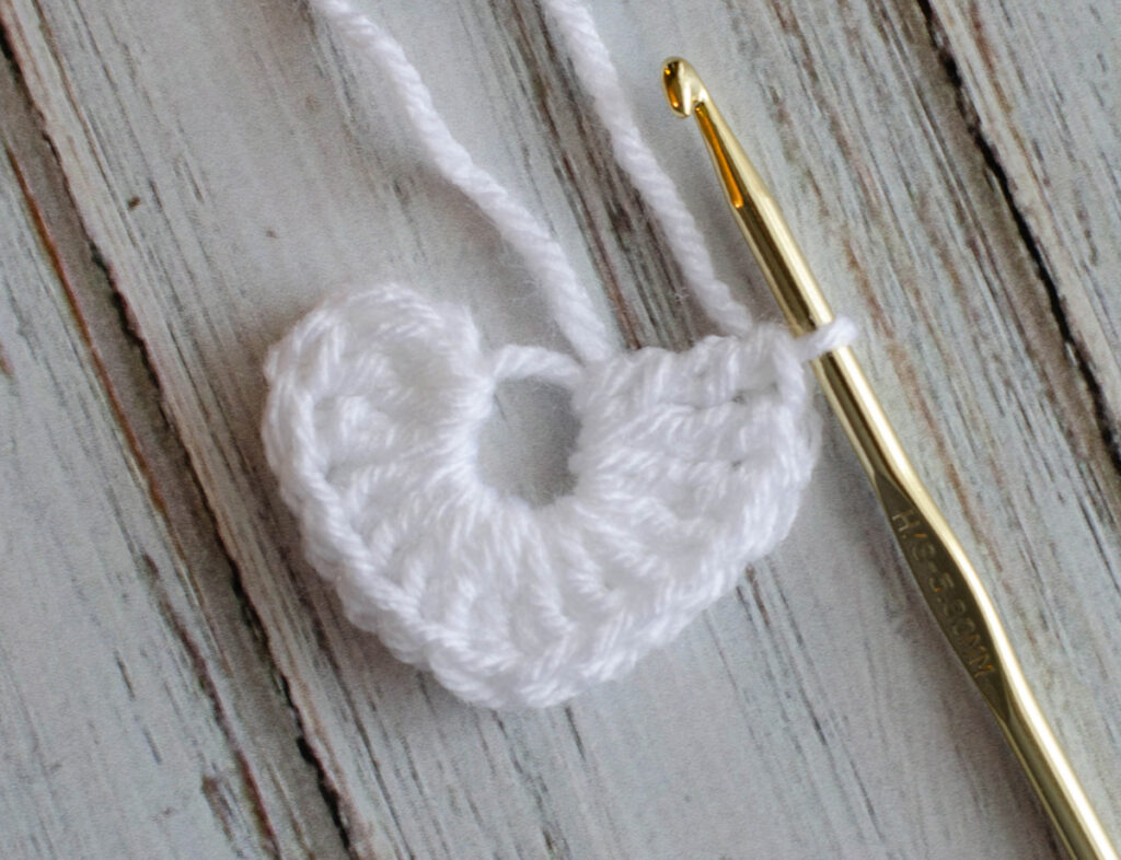 crochet hook with a white crochet heart in progress