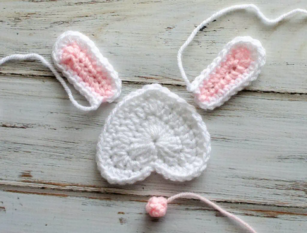 Pieces of a crochet bunny appliqué on a wood board