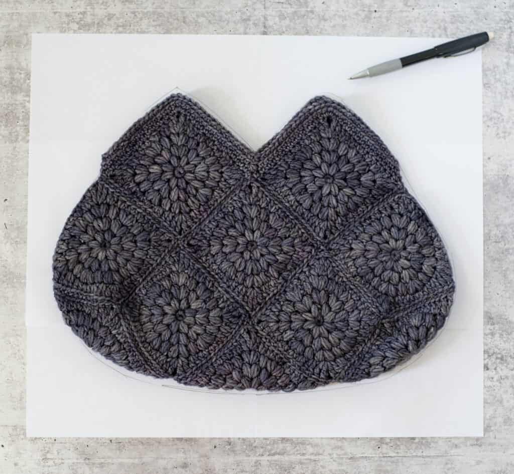 Blue crochet bag on paper on cement with pencil