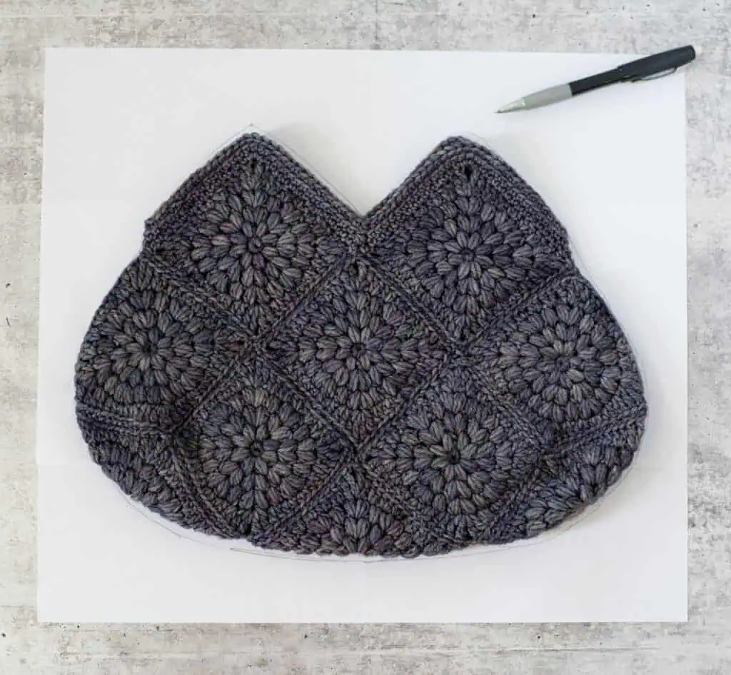 Blue crochet bag on paper on cement with pencil