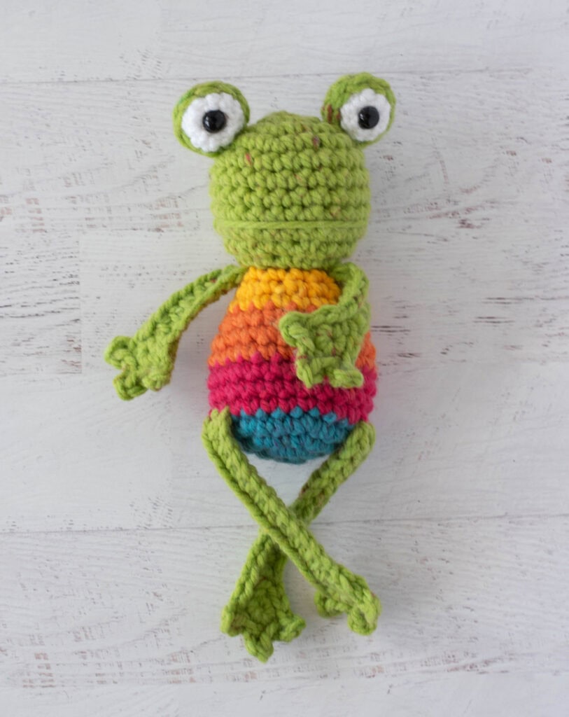 Crochet green frog with yellow, orange, red and blue striped body