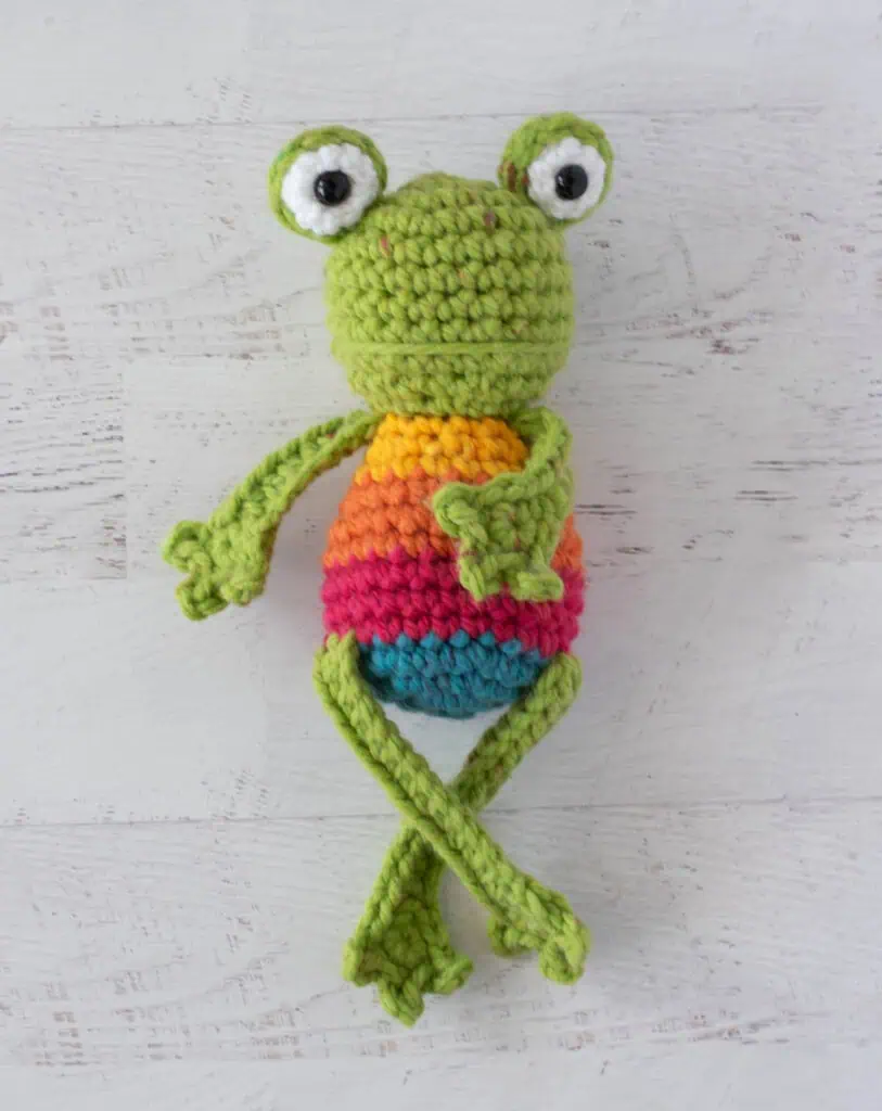 Crochet green frog with yellow, orange, red and blue striped body