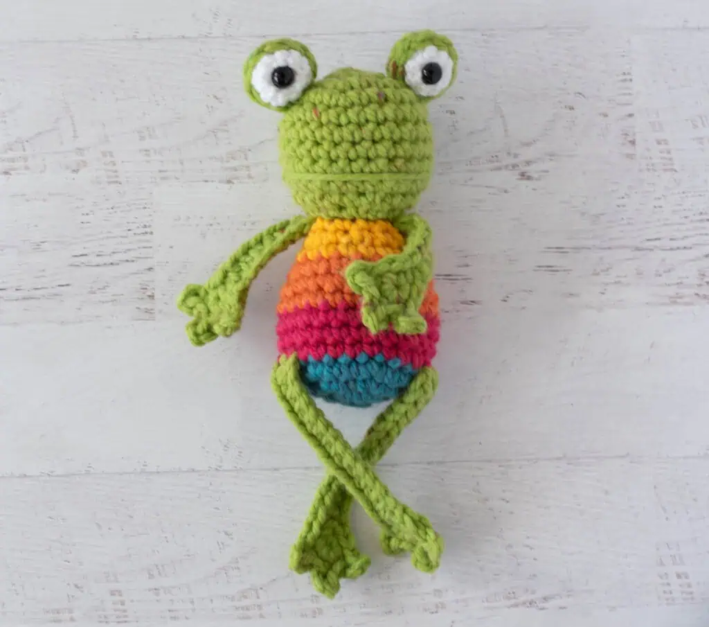 Crochet green frog with yellow, orange, red and blue striped body