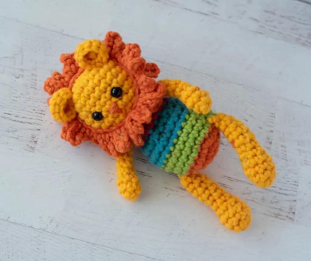 A yellow and orange rochet lion with a rainbow striped body