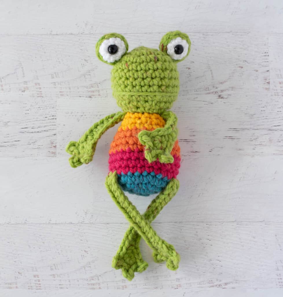 Crochet green frog with yellow, orange, red and blue striped body