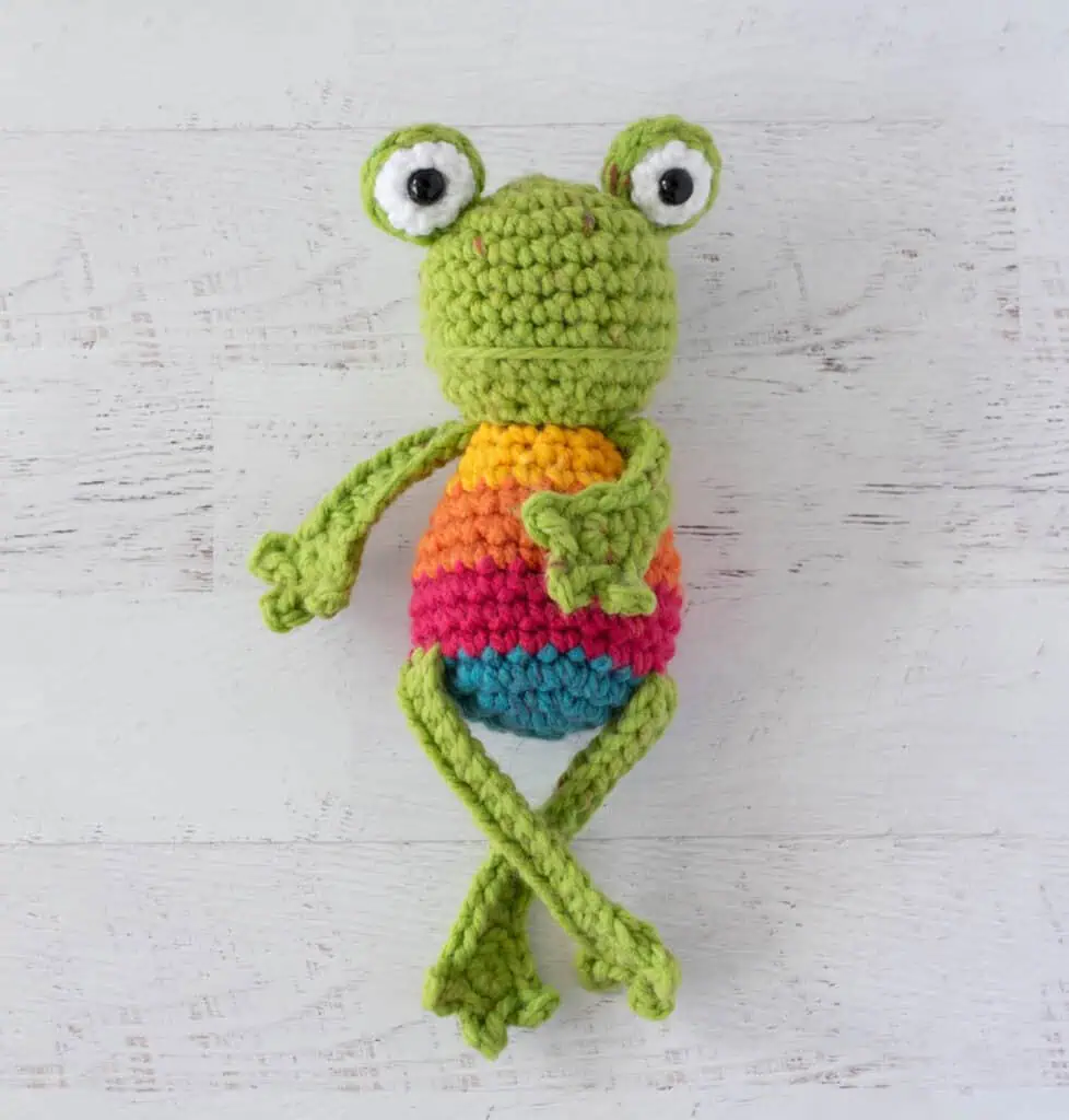 Crochet green frog with yellow, orange, red and blue striped body