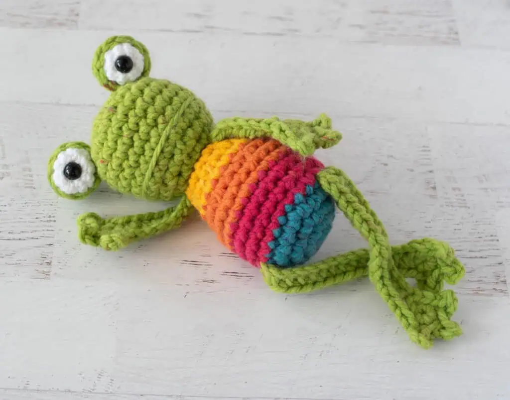 Crochet green frog with yellow, orange, red and blue striped body