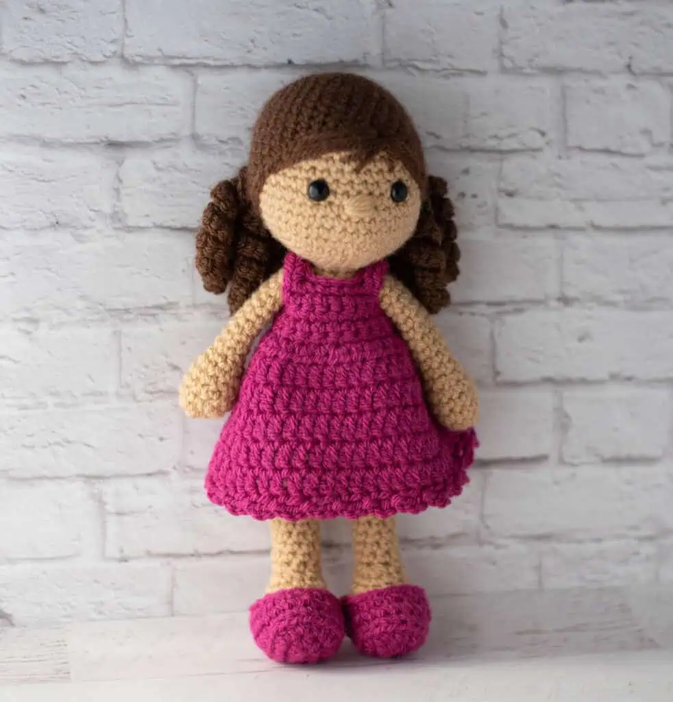 Crochet doll with brown hair and pink dress and shoes