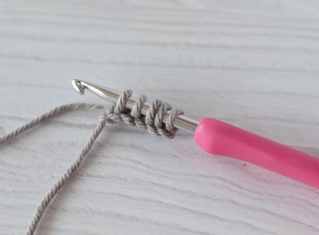 crochet strap in gray yarn with a pink crochet hook