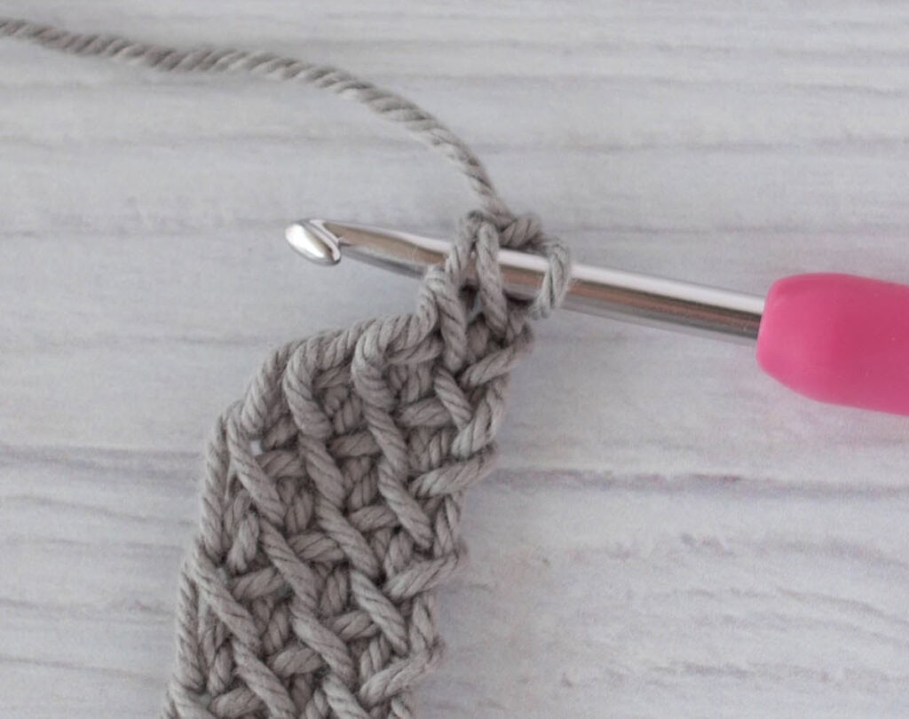 crochet strap in gray yarn with a pink crochet hook