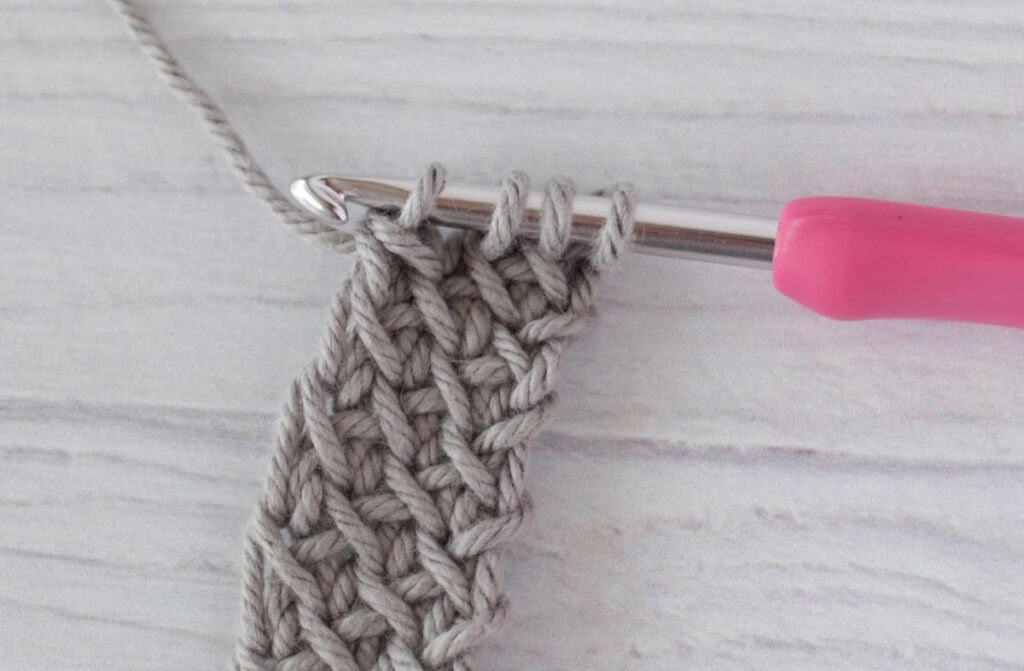 crochet strap in gray yarn with a pink crochet hook