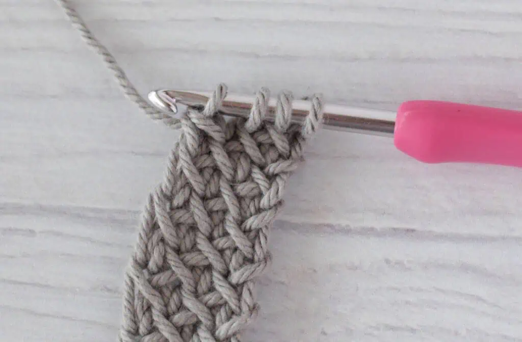 crochet strap in gray yarn with a pink crochet hook