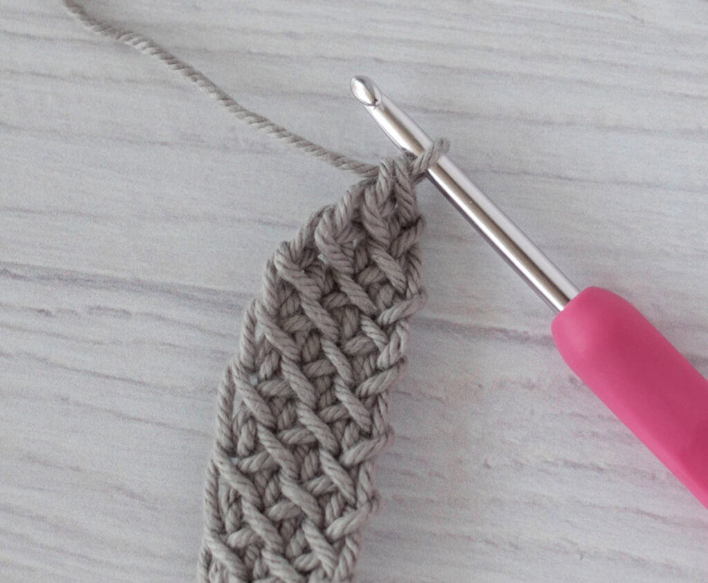 crochet strap in gray yarn with a pink crochet hook