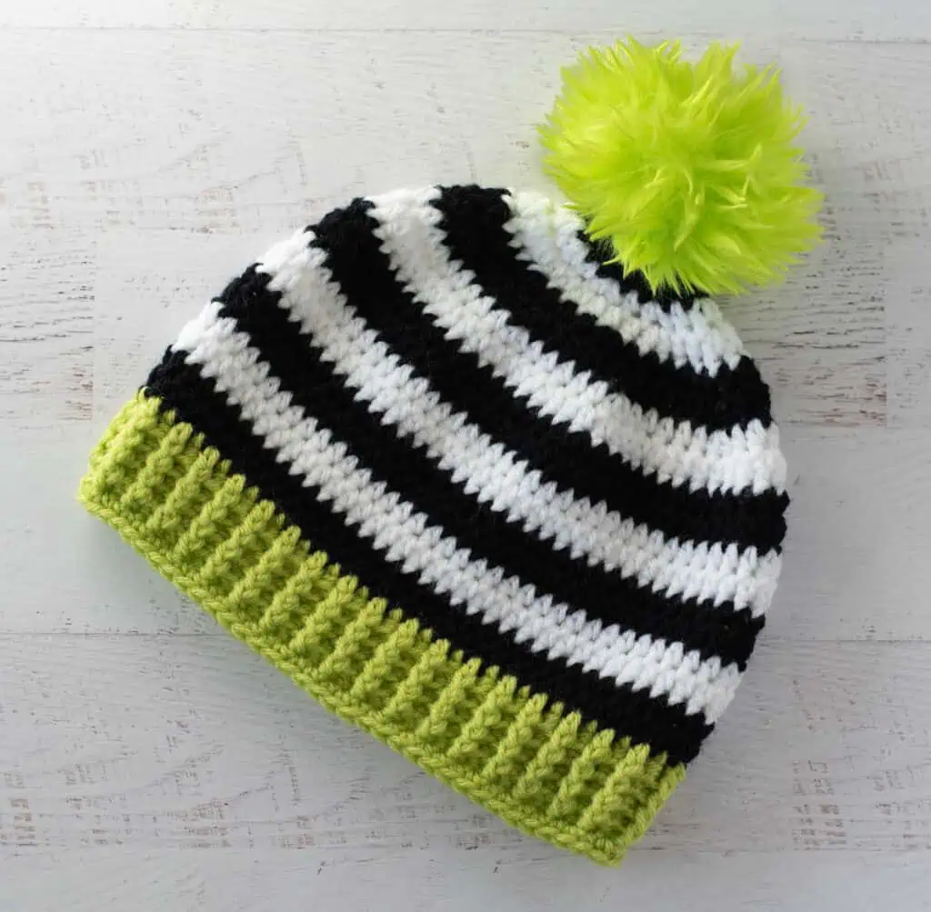 Black and white crocheted beanie with bright green brim and pom pom