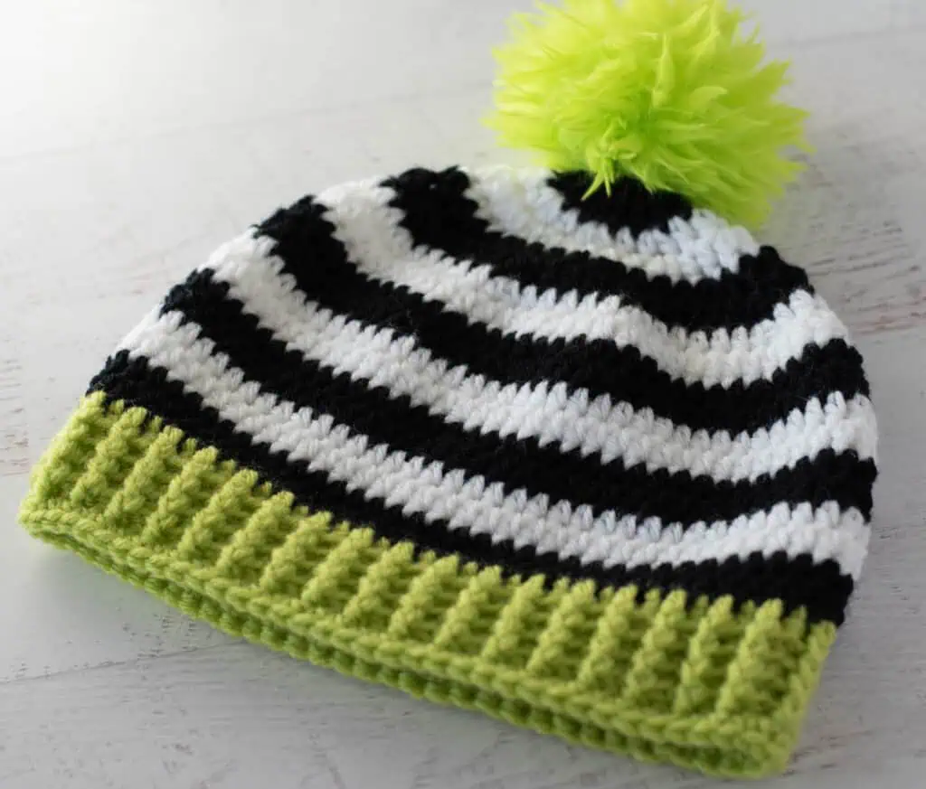 Black and white crocheted beanie with bright green brim and pom pom