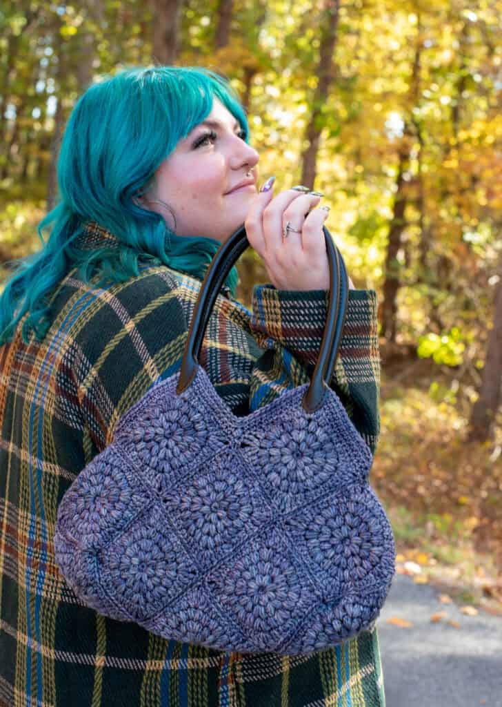 Girl with blue hair in fall street scene holding blue crochet bag