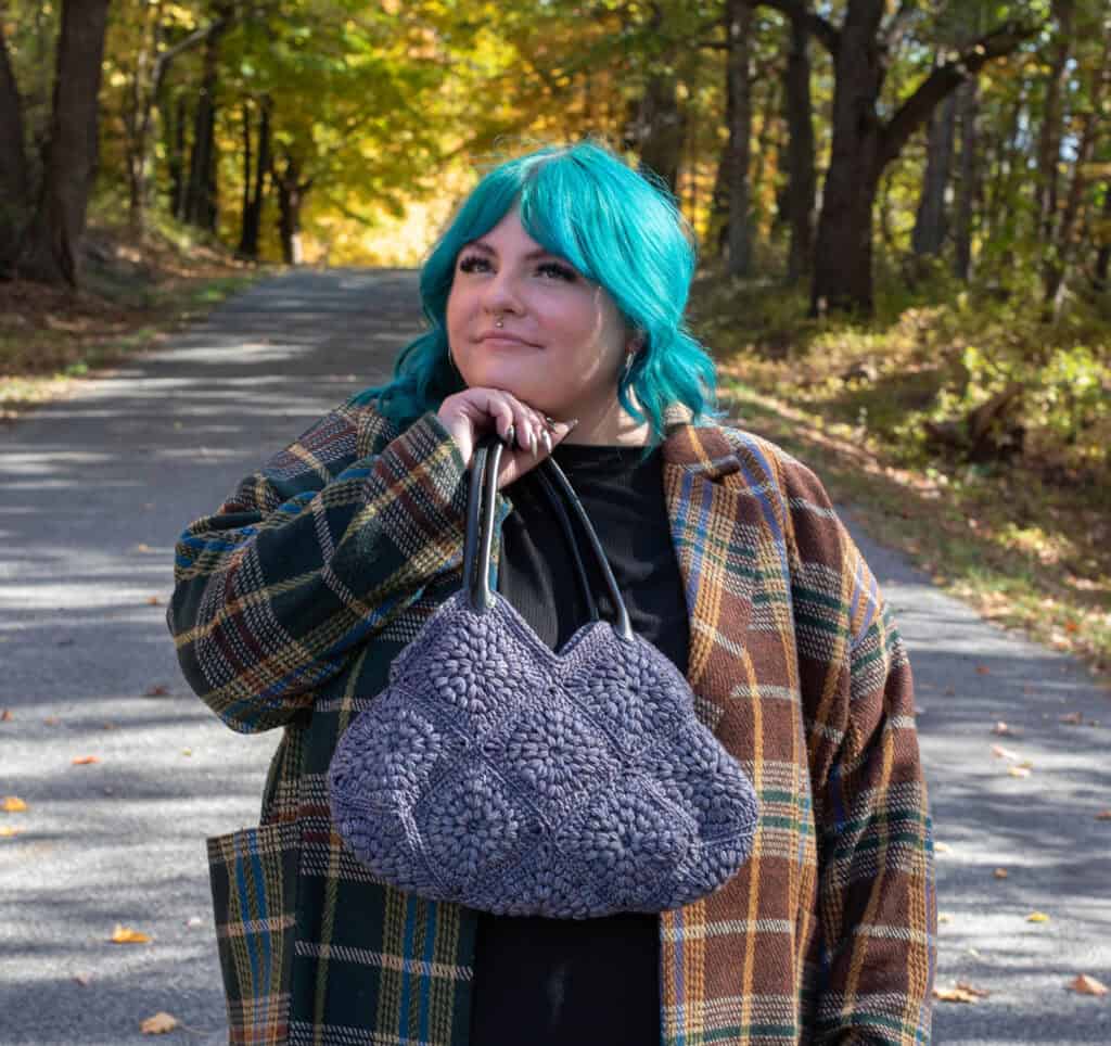 Girl with blue hair in fall street scene holding blue crochet bag