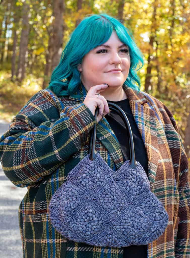 Girl with blue hair in fall street scene holding blue crochet bag