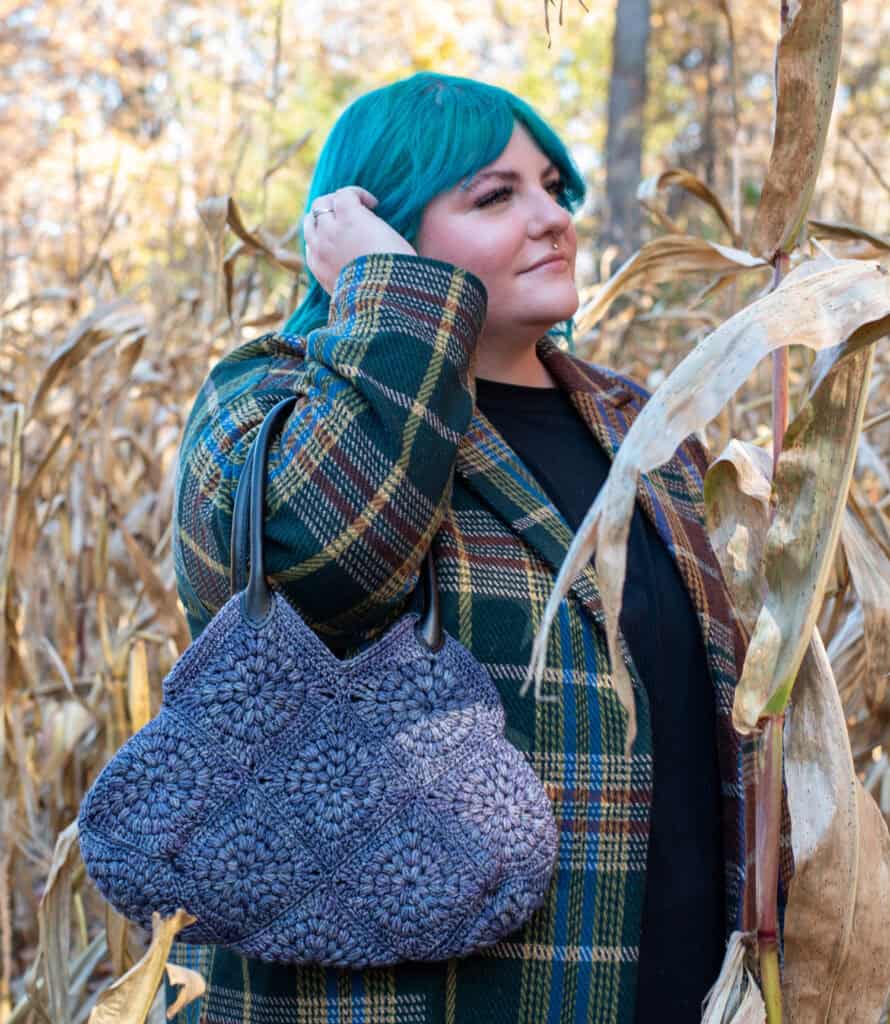 Girl with blue hair in fall street scene holding blue crochet bag