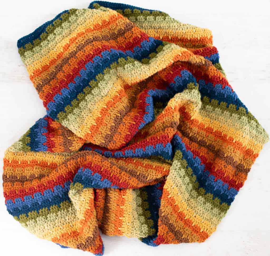 Crochet scrap afghan in multiple shades of green, orange, brown, red, blue and yellow yarn