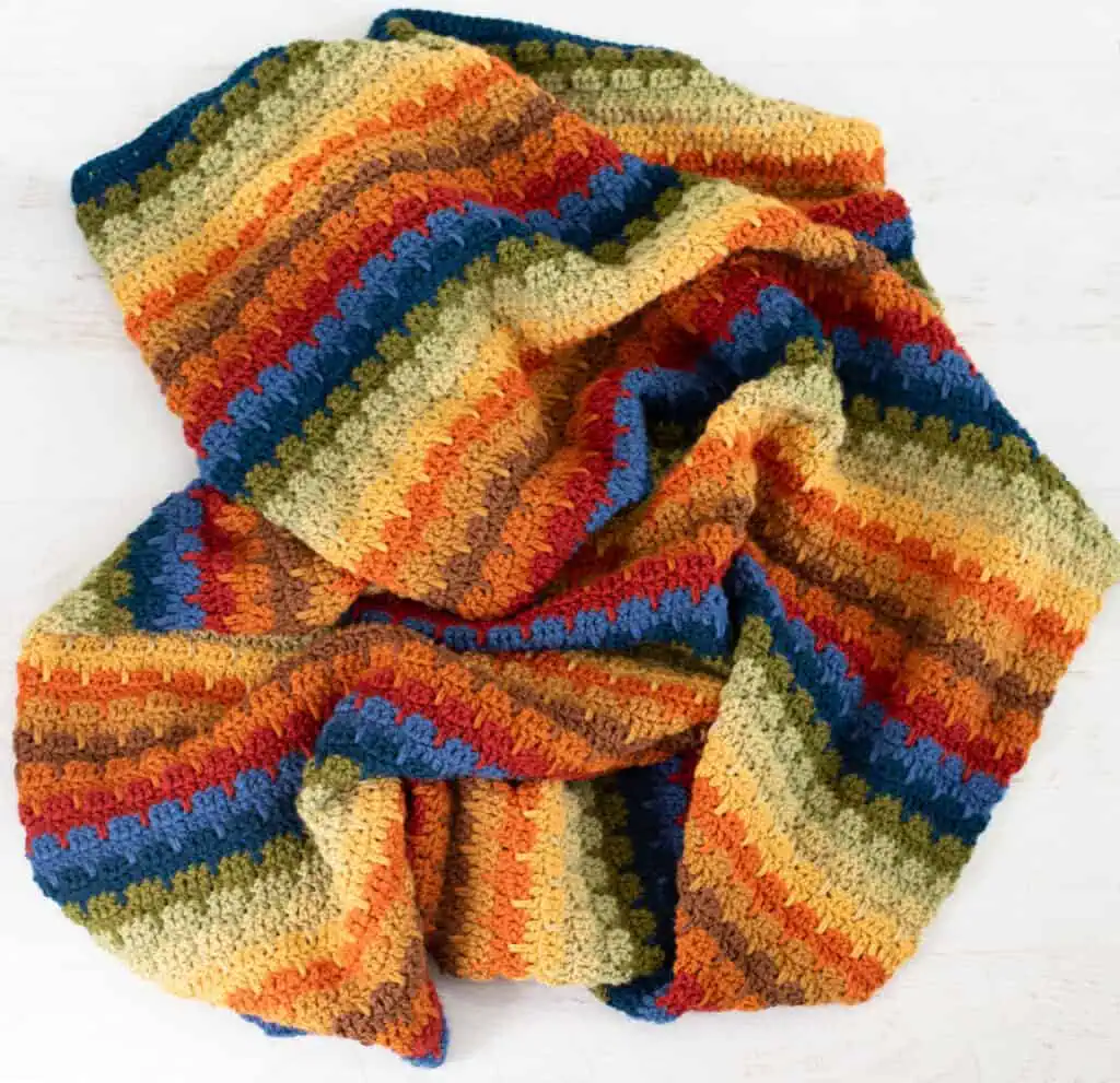 Crochet scrap afghan in multiple shades of green, orange, brown, red, blue and yellow yarn