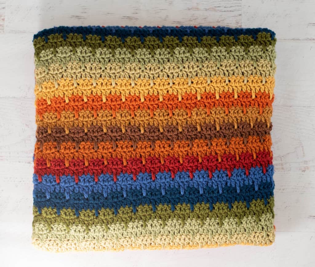 Crochet scrap afghan in multiple shades of green, orange, brown, red, blue and yellow yarn
