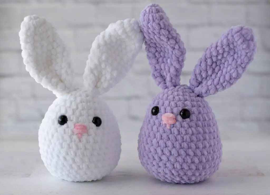 White and purple plush crochet bunnies with pink noses