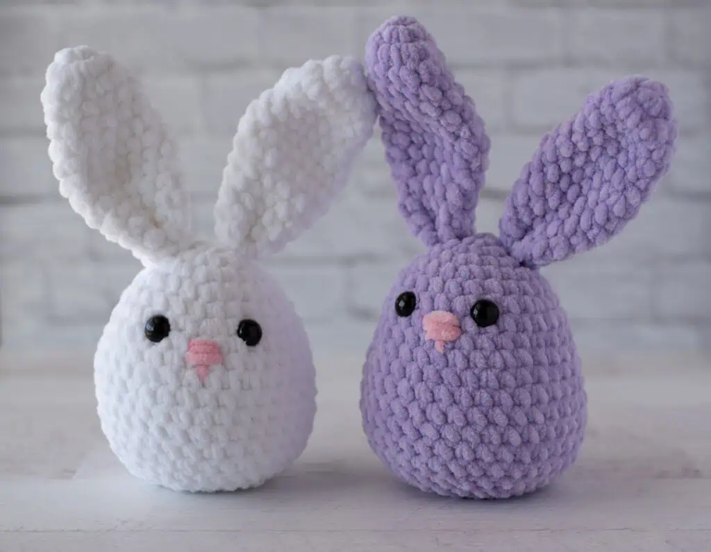 White and purple plush crochet bunnies with pink noses
