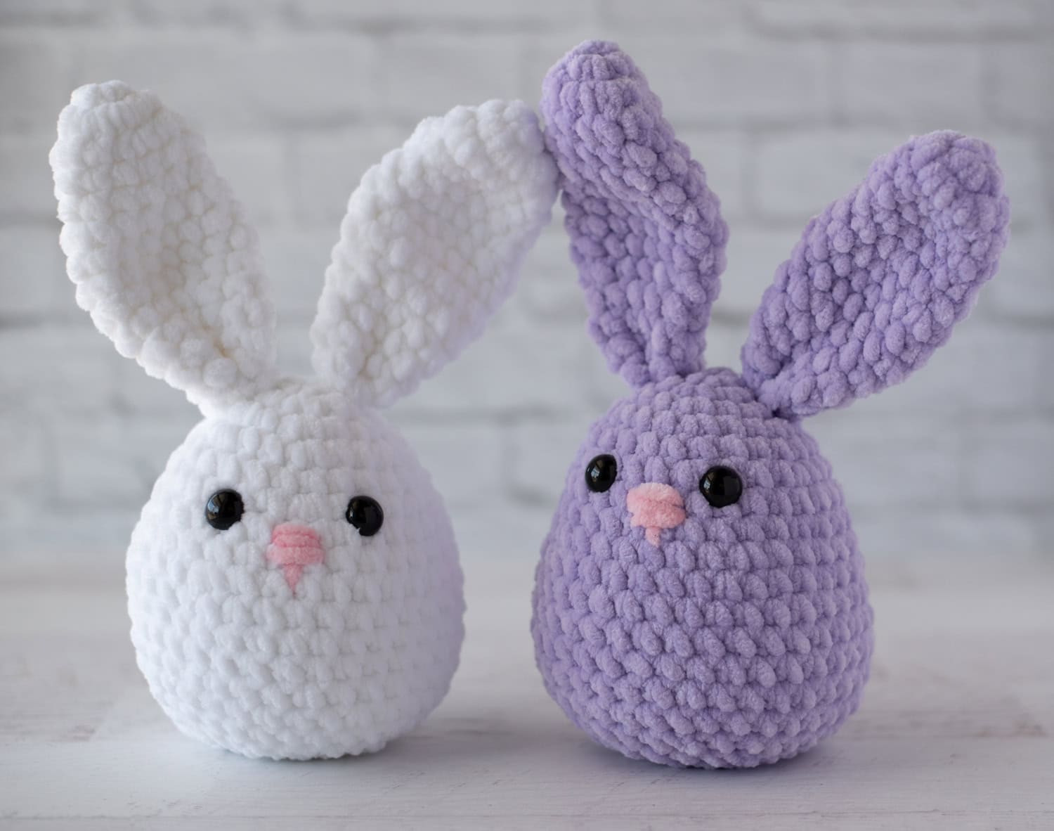 White and purple plush crochet bunnies with pink noses