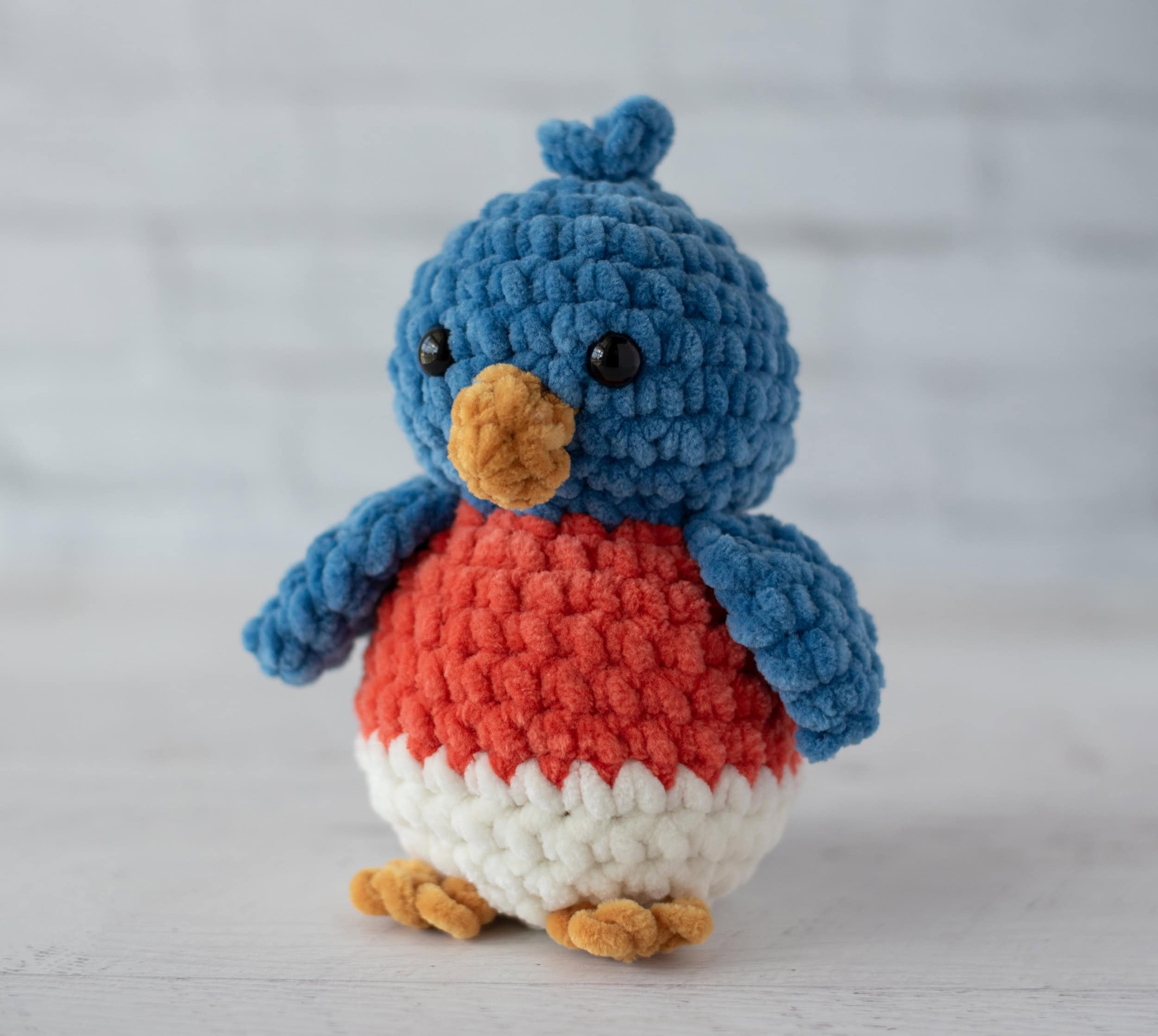 crochet bluebird out of plush blue, mango, cream and gold yarn