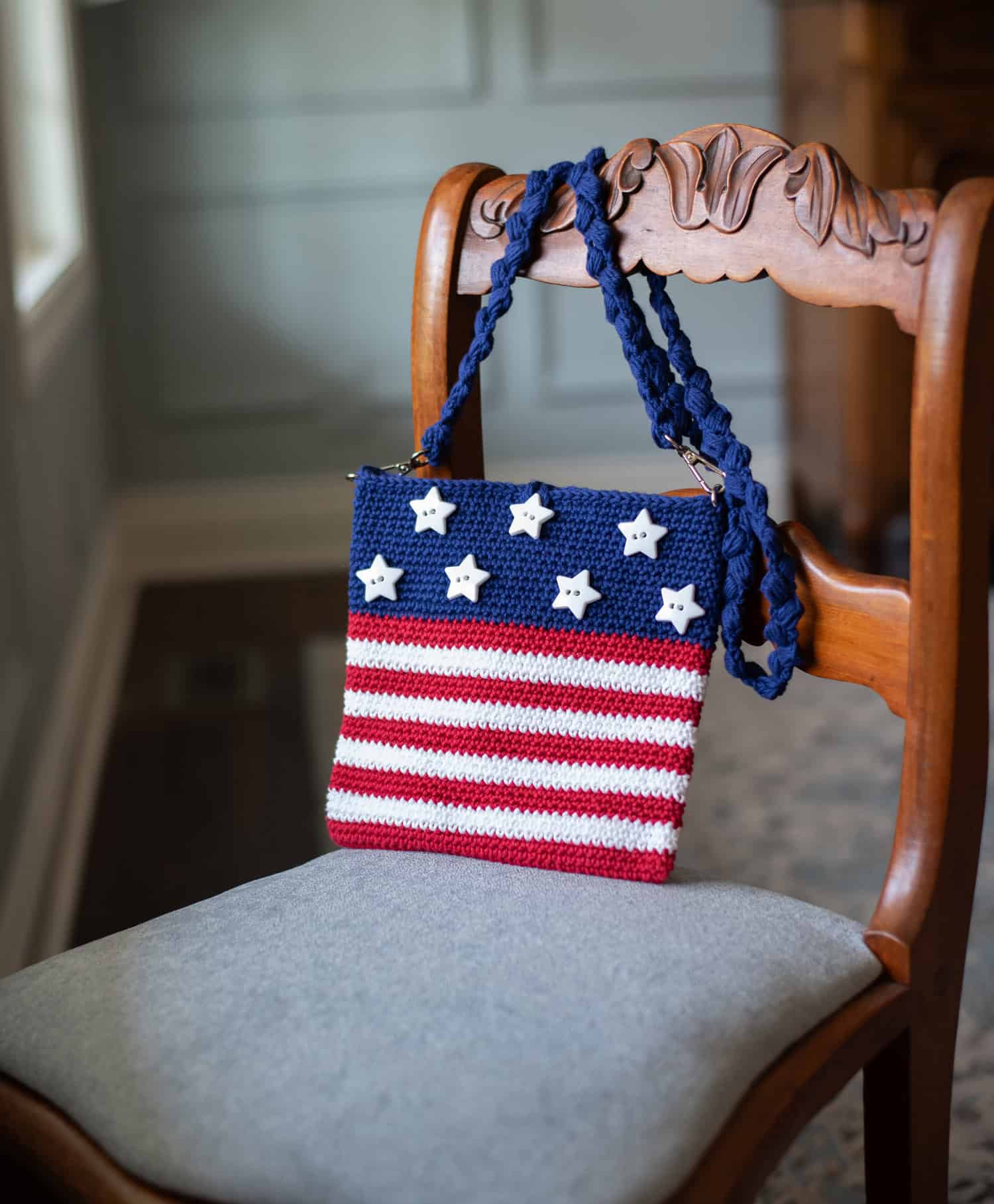 A crocheted american flag purse on a chair.