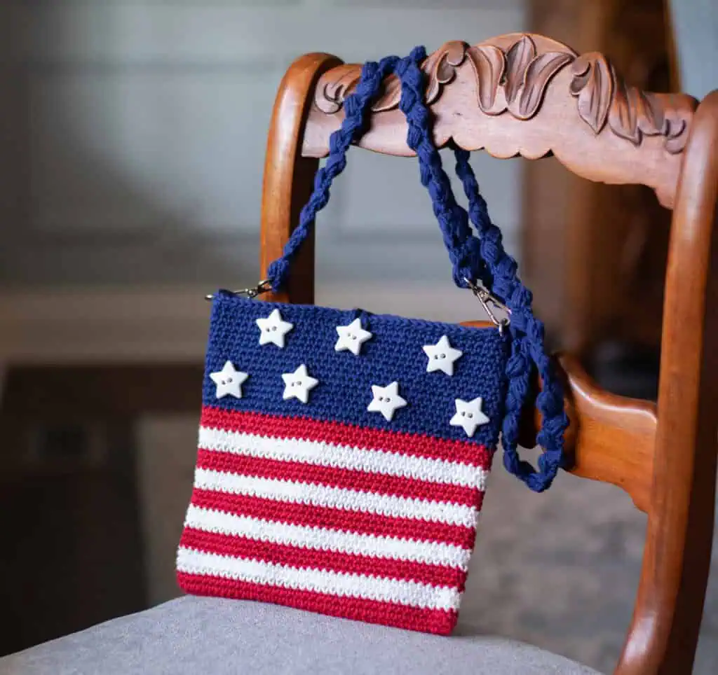 A crocheted purse with stars and stripes on a chair.