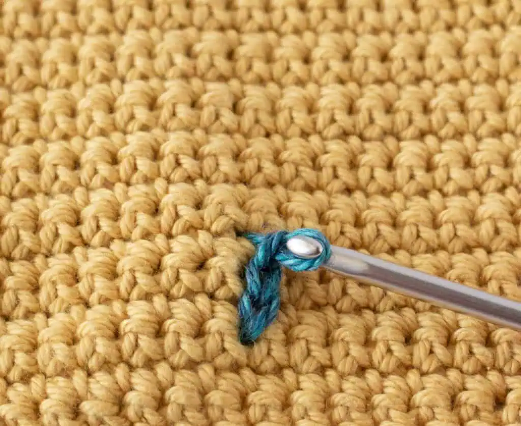 Yellow single crochet swatch with a blue yarn stitch and a pink crochet hook