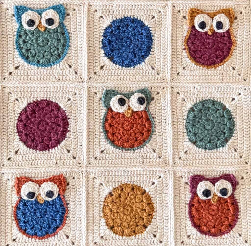 Crochet owl blanket with cream background, red, gold, green and blue owls