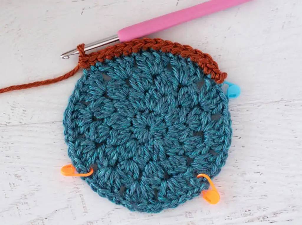 blue crochet motif with orange border and pink crochet hook
