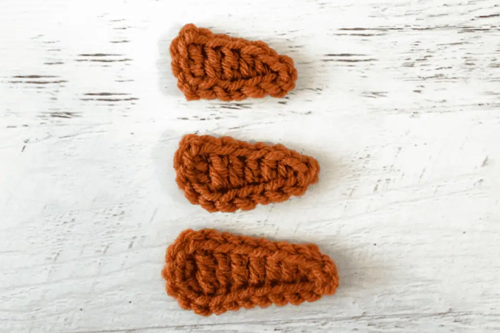 orange crochet carrot appliques on white wood background