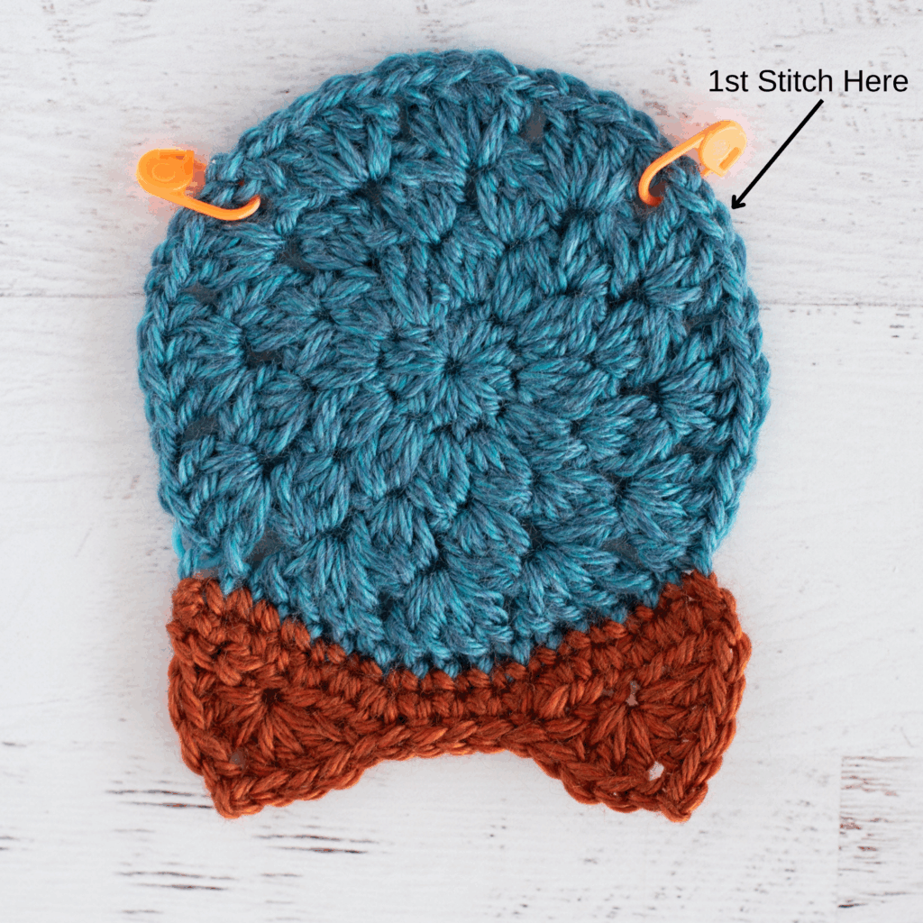 Crochet blue and orange motif with stitch markers and labeled spot to start crocheting