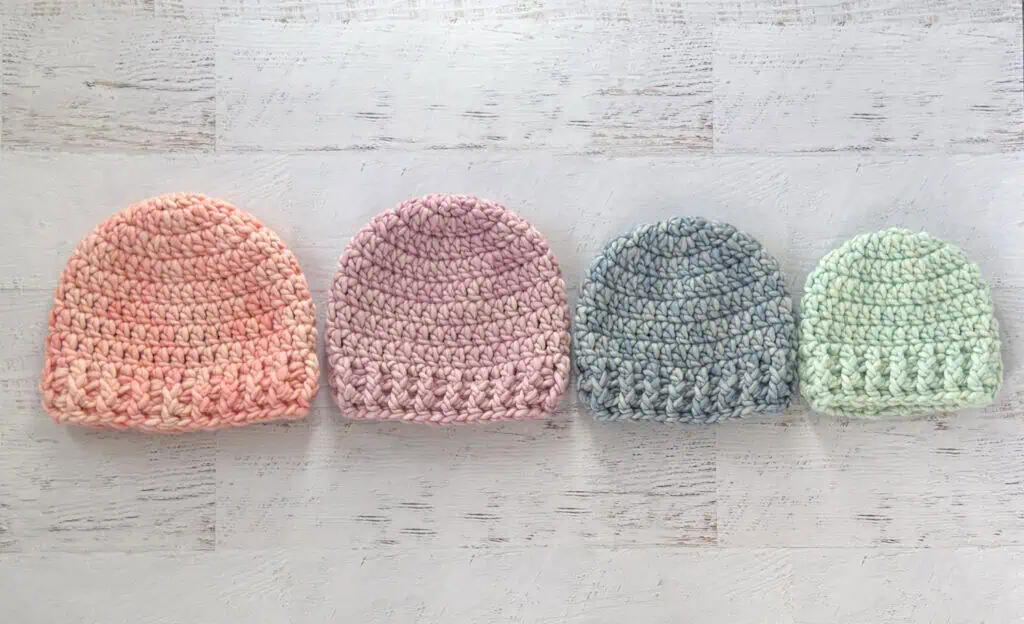 4 crochet hats in pink, purple, blue and green yarn.
