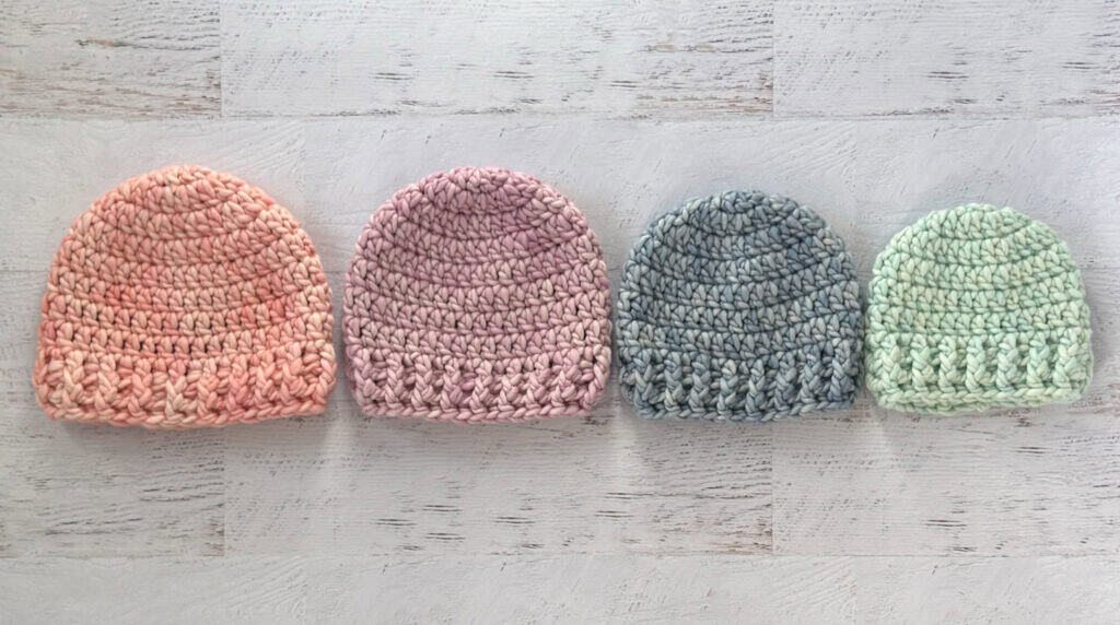 4 crochet hats in pink, purple, blue and green yarn.