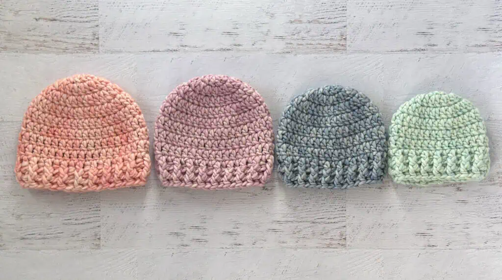 4 crochet hats in pink, purple, blue and green yarn.