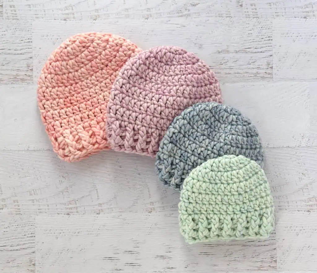 4 crochet hats in pink, purple, blue and green yarn.