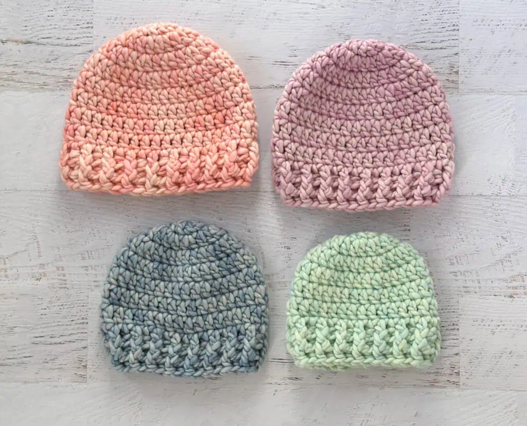 4 crochet hats in pink, purple, blue and green yarn.