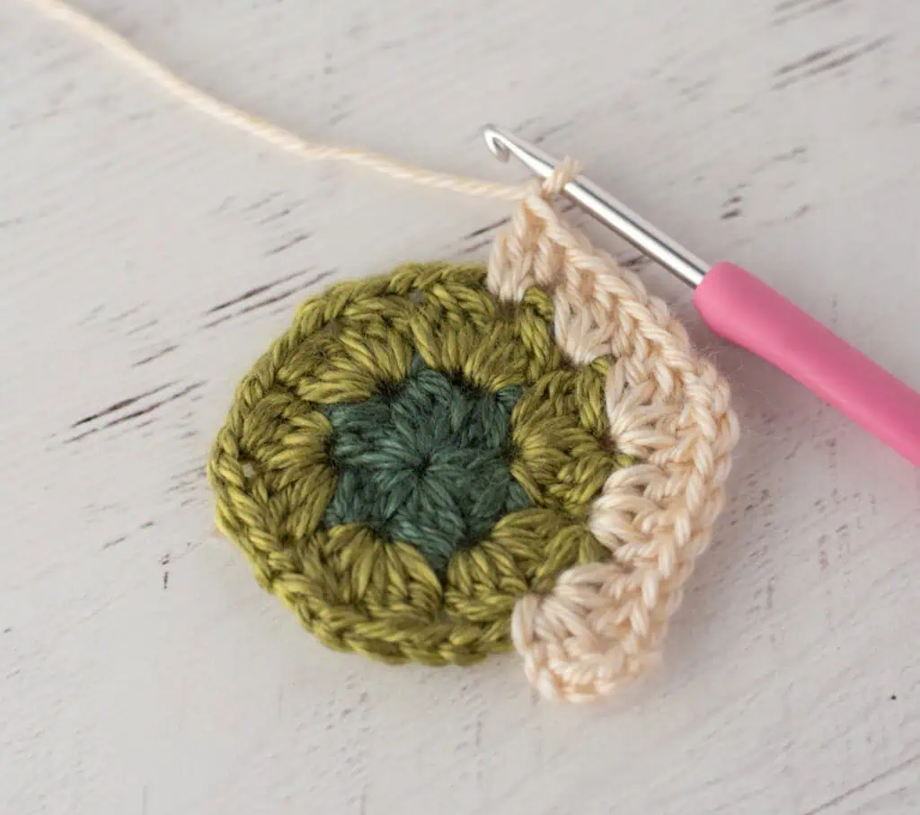 Close-up of crochet granny hexagons made with colorful yarn and a pink crochet hook.