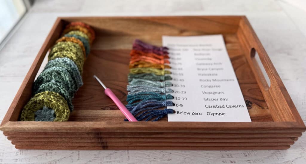 Wood tray with crochet motifs and pink crochet hook placed next to a window
