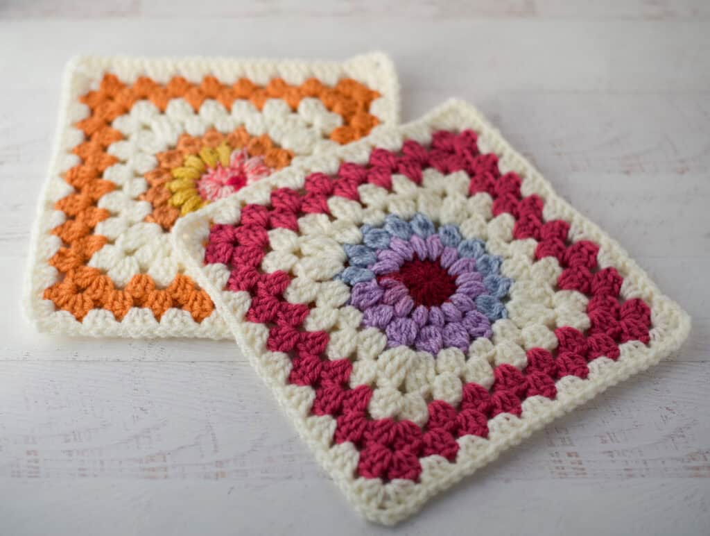 2 Sunburst granny afghan squares on a white washed table