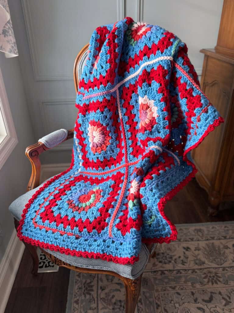 Colorful crochet afghan on a chair by a window