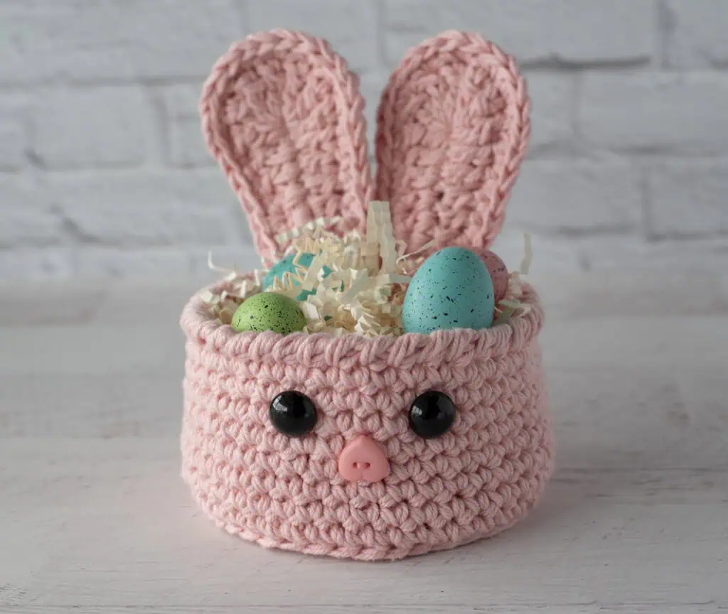 pink crochet bunny basket with decorative grass and Easter eggs